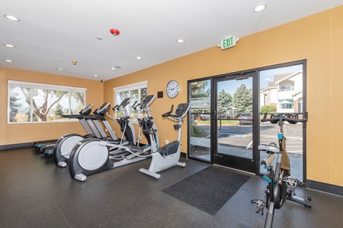 A gym with a row of exercise bikes and a clock on the wall.