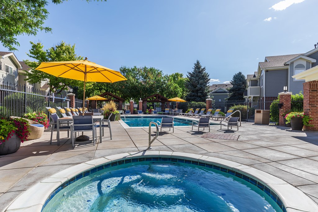 A pool area with a hot tub and lounge chairs.