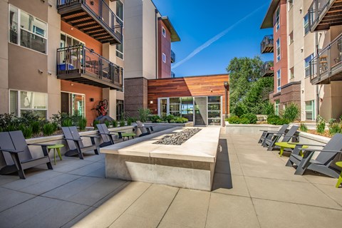 A sunny day at a modern apartment complex with a courtyard and seating area.