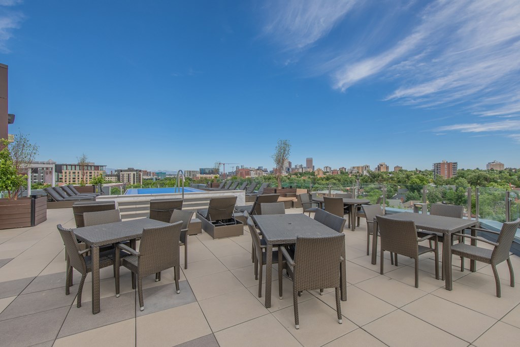 A patio with tables and chairs overlooking a city skyline.
