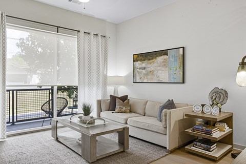 A living room with a white couch, a coffee table, and a painting on the wall.