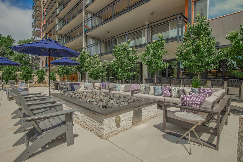 Outdoor lounge area with chairs, umbrellas, and a fire pit.