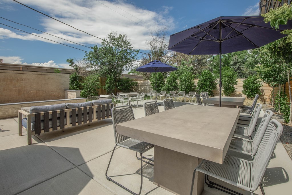A patio with a table and chairs under umbrellas.