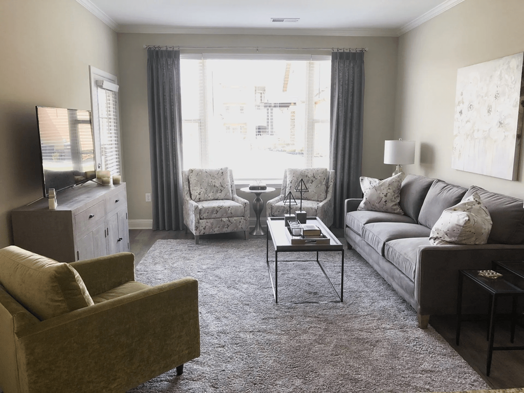 A living room with a brown sofa, a white armchair, and a grey chair.