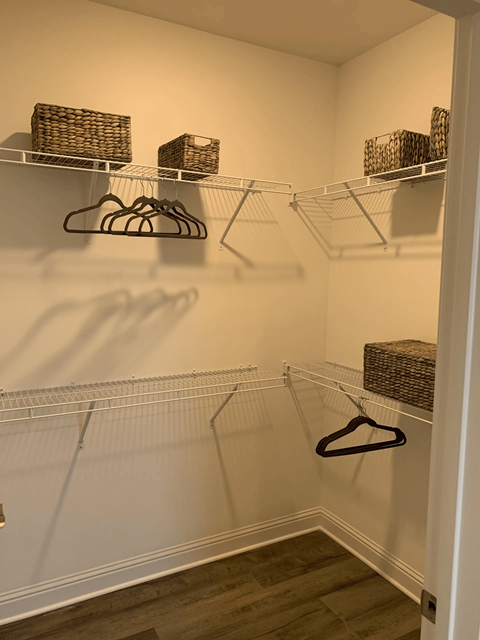 A white closet with a hanger and baskets on the shelf.