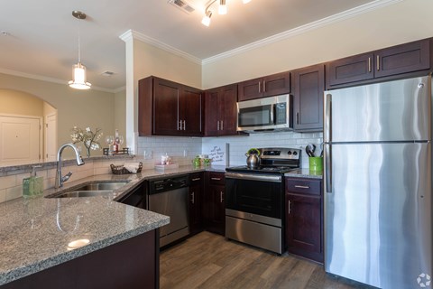 A kitchen with dark wood cabinets and stainless steel appliances.