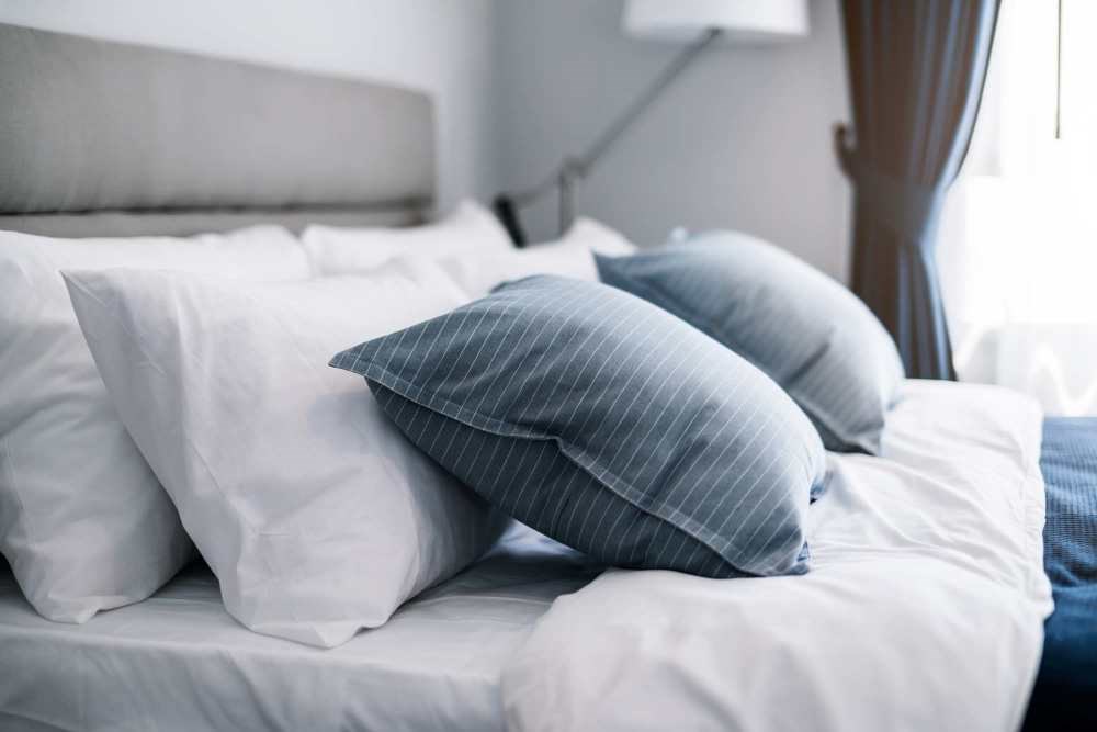 A bed with white and blue pillows.