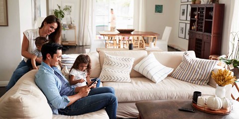 A family of four is sitting on a couch in a living room.