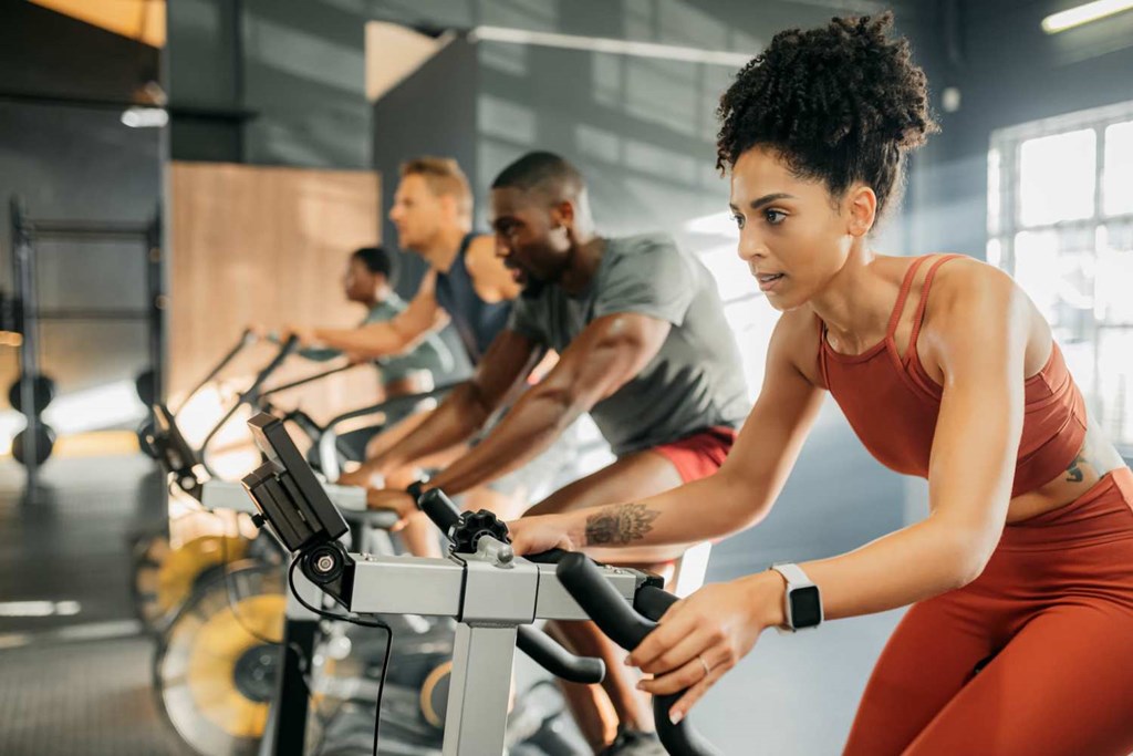 A group of people are working out on exercise bikes in a gym.