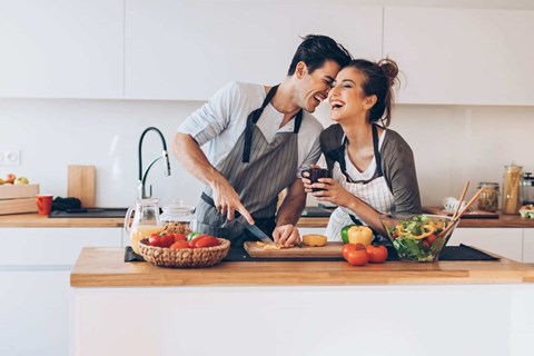 A man and woman are preparing food together in a kitchen.