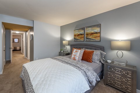A bedroom with a large bed and two lamps.