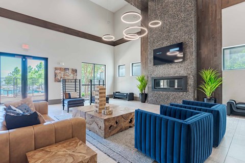 A living room with a brown couch, blue chairs, and a television mounted on the wall.