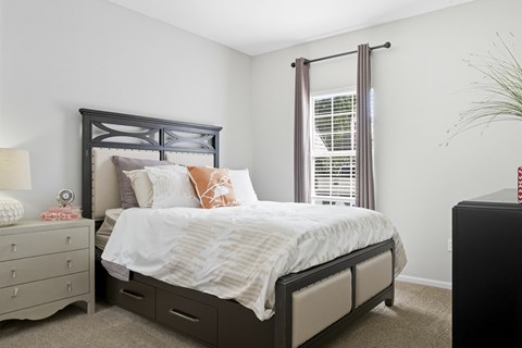 A bedroom with a large bed and a nightstand with a lamp.
