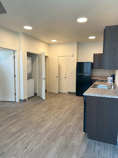 A kitchen with a black fridge and wooden cabinets.
