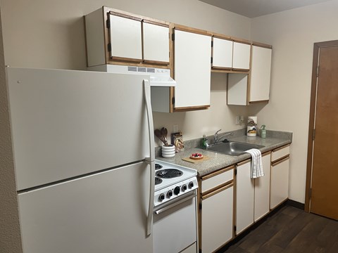 A kitchen with a white refrigerator, stove, and cabinets.