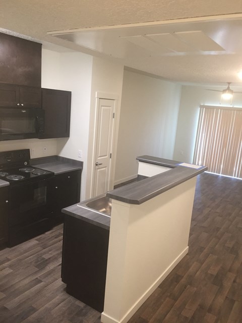A kitchen with a black counter top and a white wall.