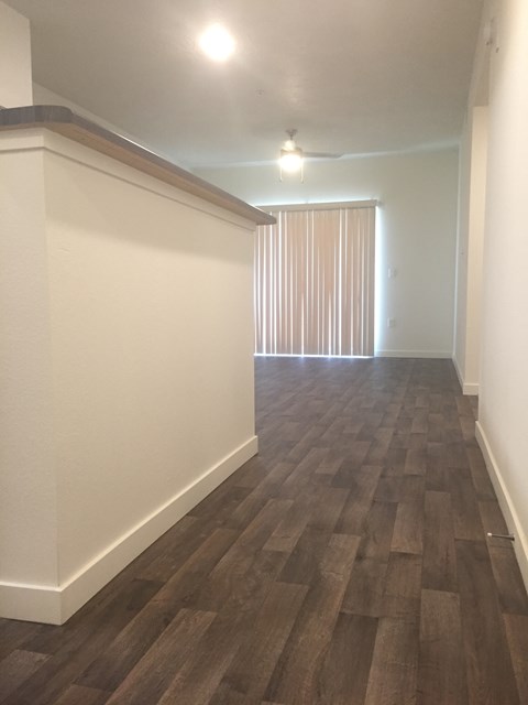 A long hallway with wood flooring and white walls.