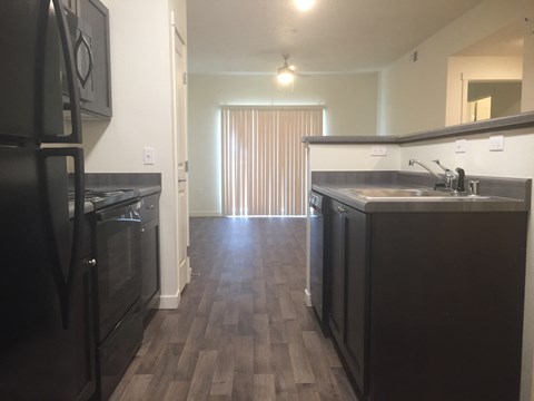 A kitchen with dark wood floors and black appliances.
