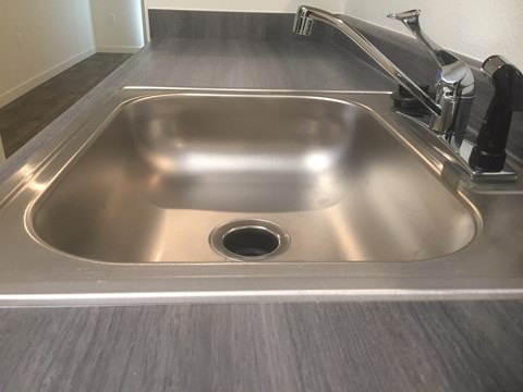 A stainless steel kitchen sink with a drain in the middle.