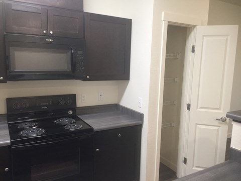 A kitchen with black cabinets and a black stove top oven.