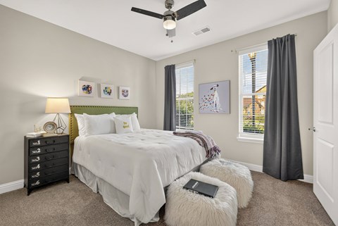 A bedroom with two beds, a ceiling fan, and a window with blinds.