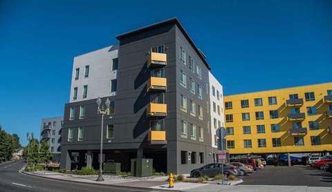 A modern multi-story building with a parking lot in front.
