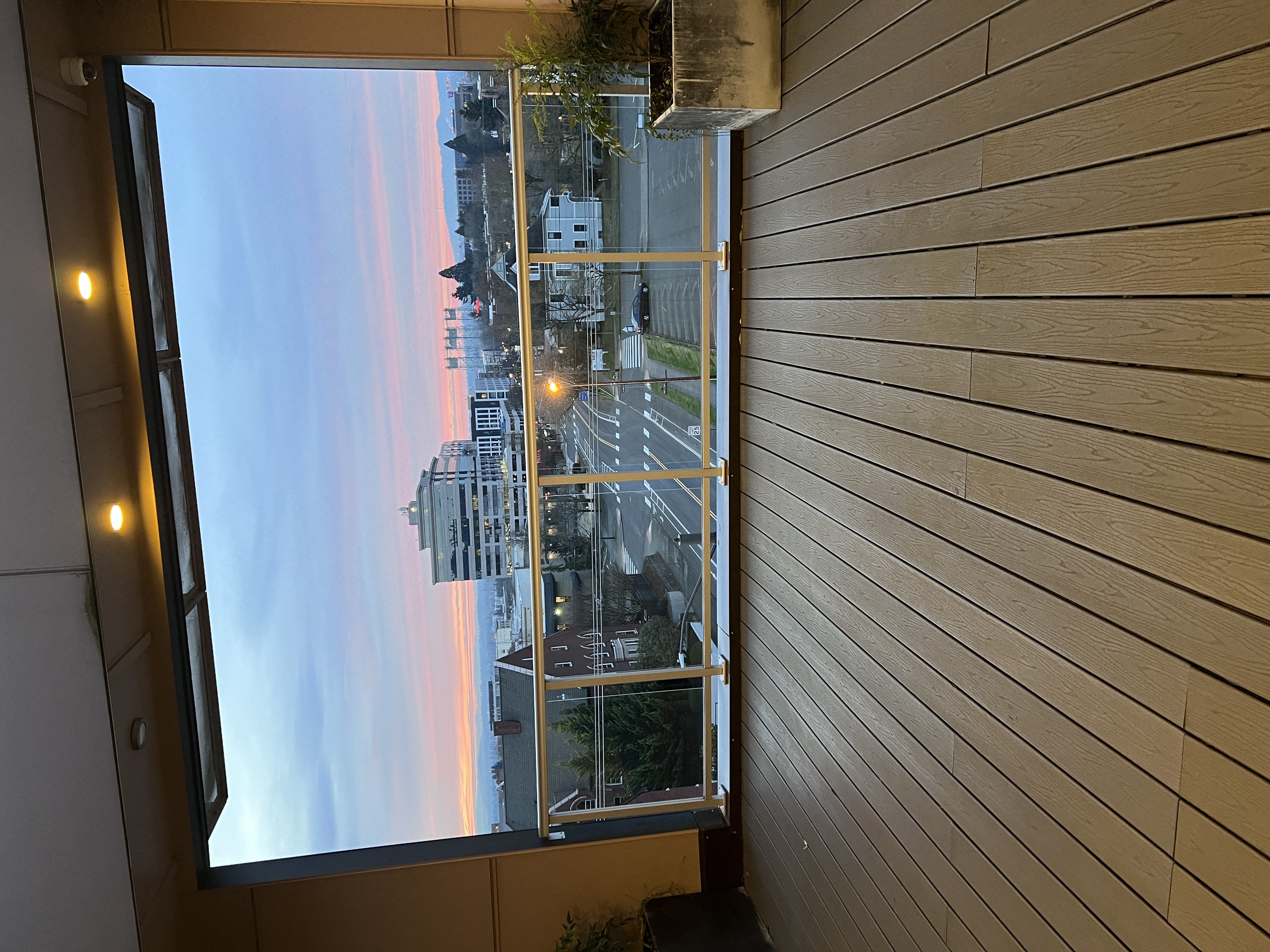 A view of a cityscape through a window with a wooden wall on the side.