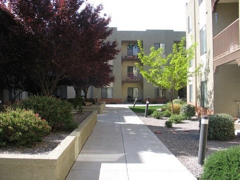 A long concrete walkway leads to a building with balconies.