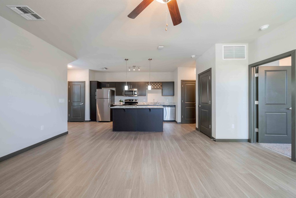 A modern kitchen with a wooden floor and a ceiling fan.