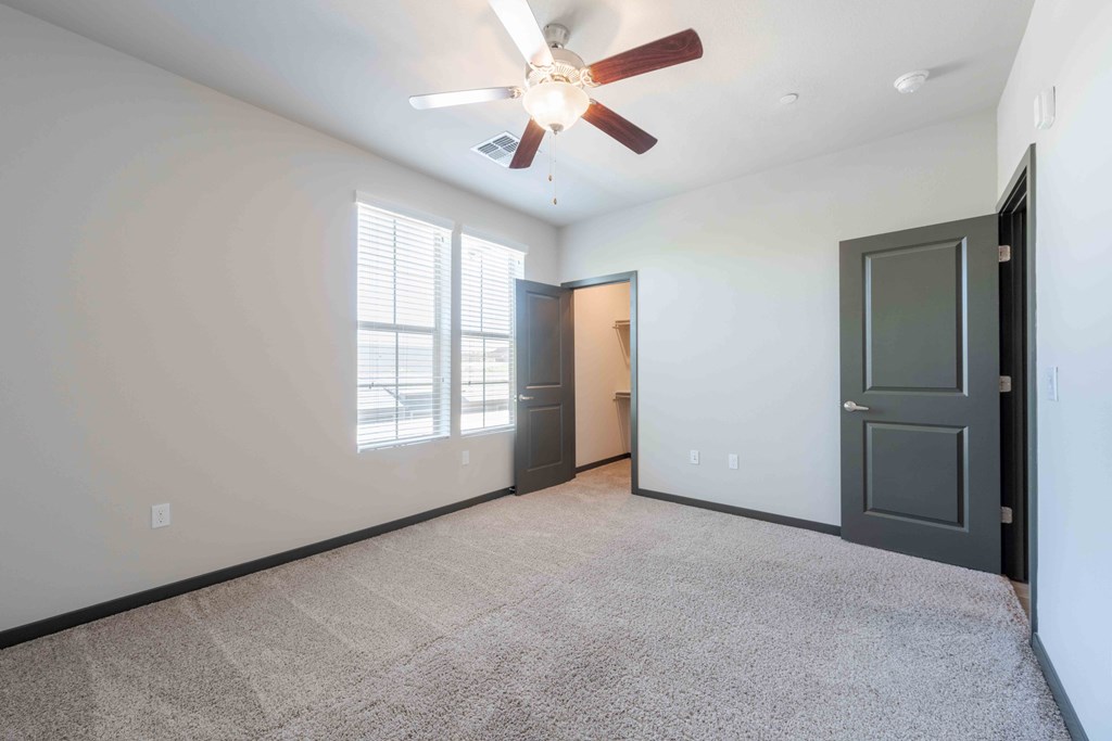 Bedroom with a ceiling fan and carpeted floor.