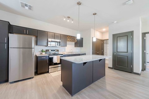 A modern kitchen with pendant lights and a large island in the center.