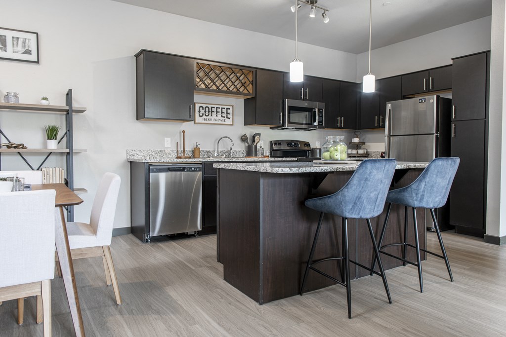 a kitchen with an island with bar stools and a stainless steel refrigerator