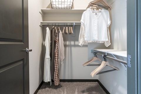 a walk in closet with clothes hanging on a rack and a sink
