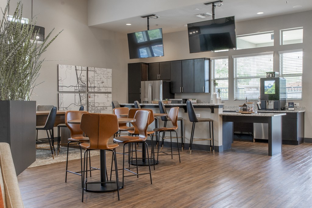 a clubhouse with tables and chairs and a kitchen with a tv