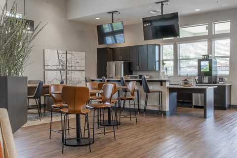 a clubhouse with tables and chairs and a kitchen with a tv
