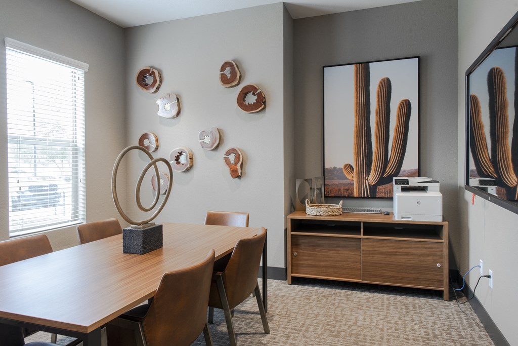 a conference room with a table and chairs and a mirror and cactus wall art