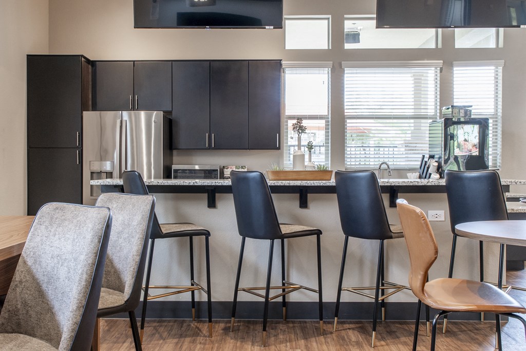 a kitchen with bar stools and chairs in front of a counter with a bar