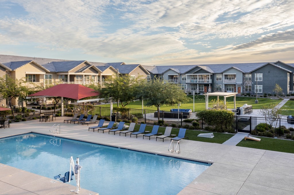a swimming pool with chairs and a building in the background