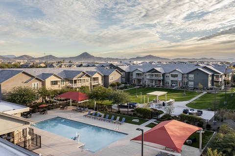 an aerial view of a pool and buildings with mountains in the background