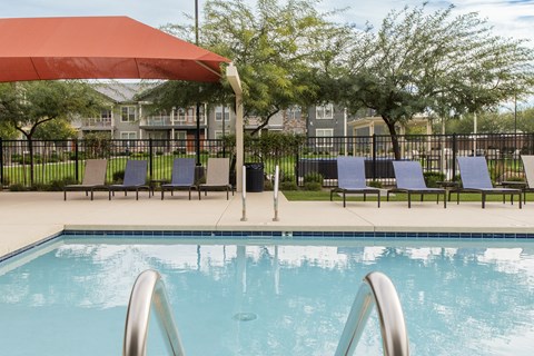 the pool at our apartments with chairs and umbrella
