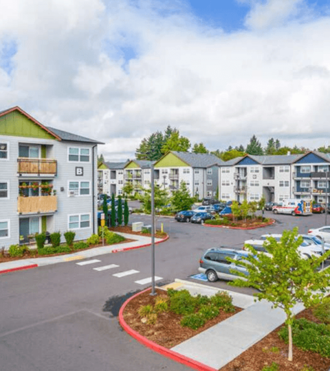 A street view of a residential area with apartment buildings and parked cars.