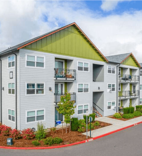 A row of modern townhouses with balconies and flower beds in front.