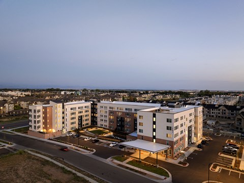 A large building complex with a parking lot in front.