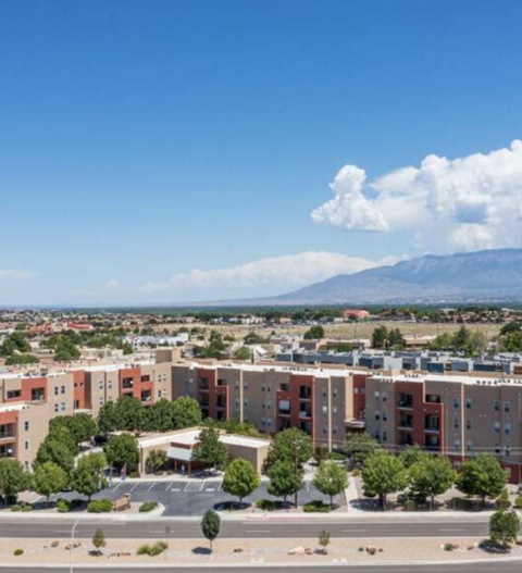 A large apartment complex with a parking lot in front and a mountain in the background.