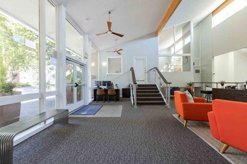 A modern office space with orange chairs and a staircase.