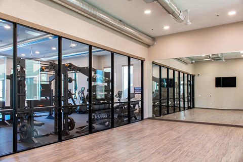 A gym with a mirrored wall and wooden floors.