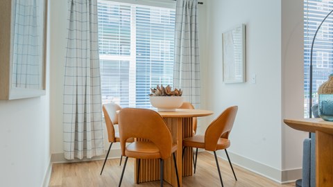 A dining table with four chairs and a bowl of fruit on top.