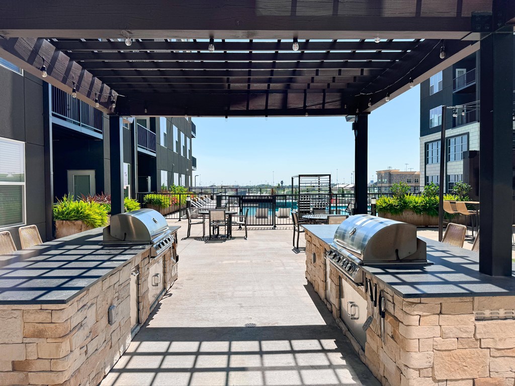 A patio with a grill and a table surrounded by buildings.