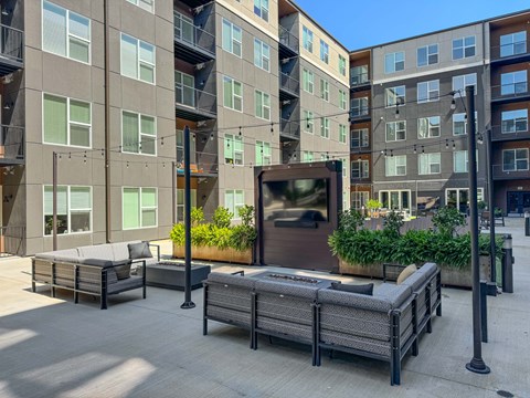A modern outdoor seating area with a large screen in front of apartment buildings.