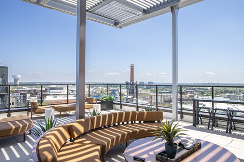 A patio with a long couch and a table with a potted plant on it.